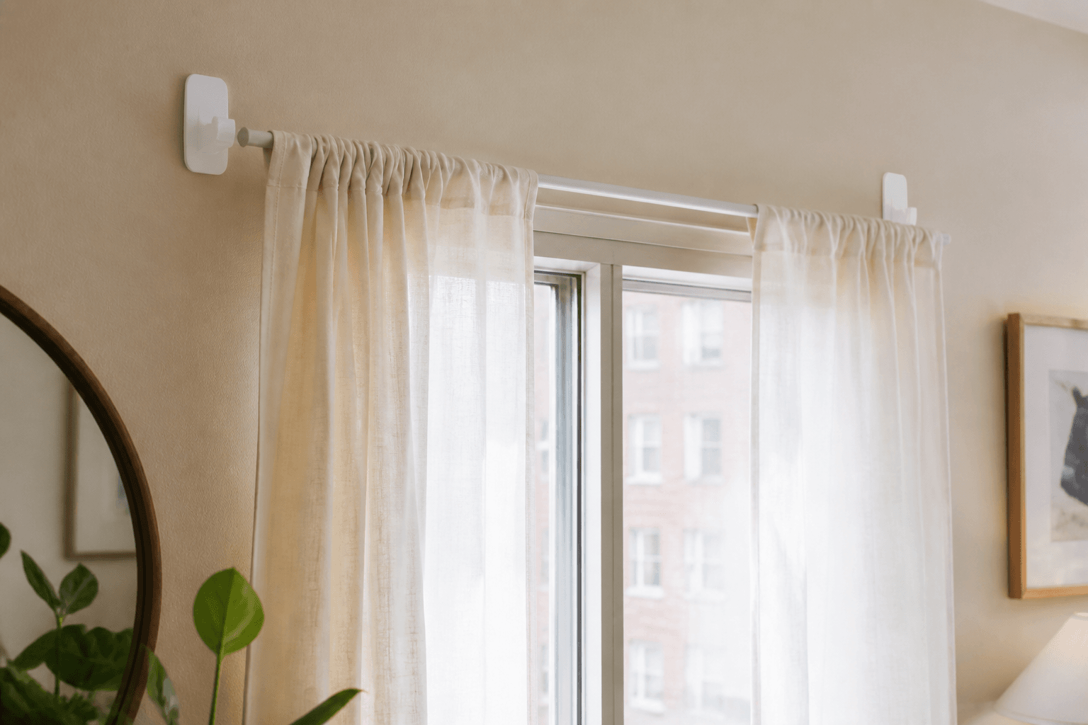 Adhesive command hooks holding a lightweight curtain rod on a rental wall